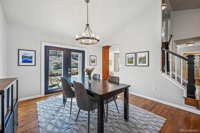 dining space with wood finished floors, a notable chandelier, baseboards, and stairs