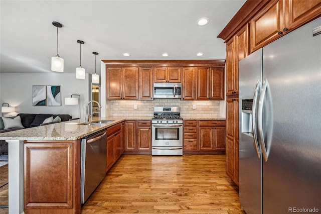 kitchen with light wood-type flooring, brown cabinetry, stainless steel appliances, and a sink