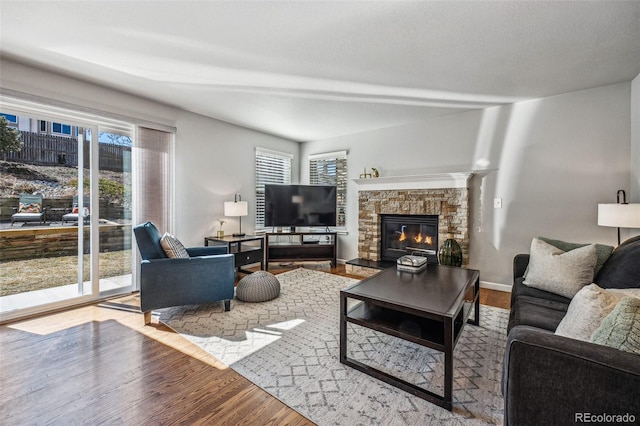 living area with a fireplace, wood finished floors, and baseboards