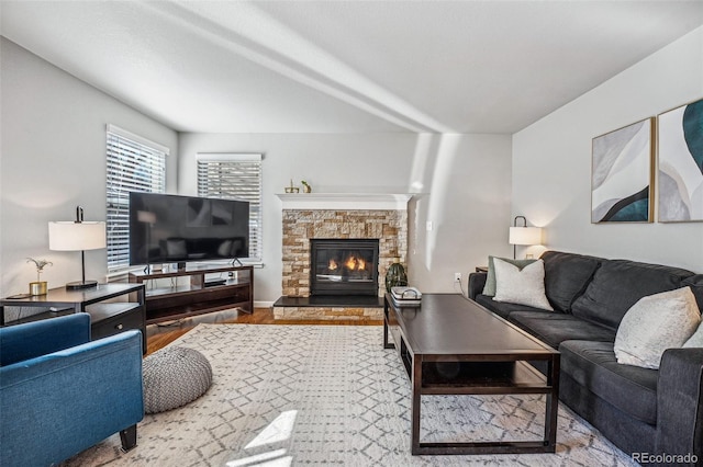 living area with a stone fireplace and wood finished floors