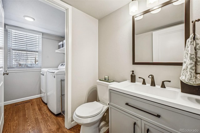 bathroom with washing machine and clothes dryer, toilet, vanity, wood finished floors, and baseboards