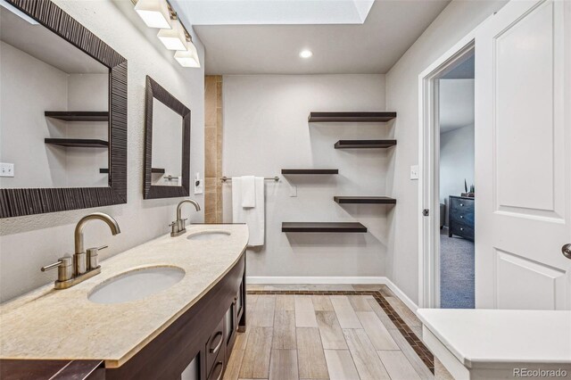 full bathroom featuring double vanity, a sink, baseboards, and wood finished floors