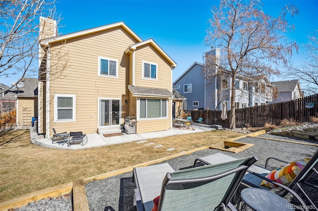 rear view of property featuring a yard, a patio area, and fence