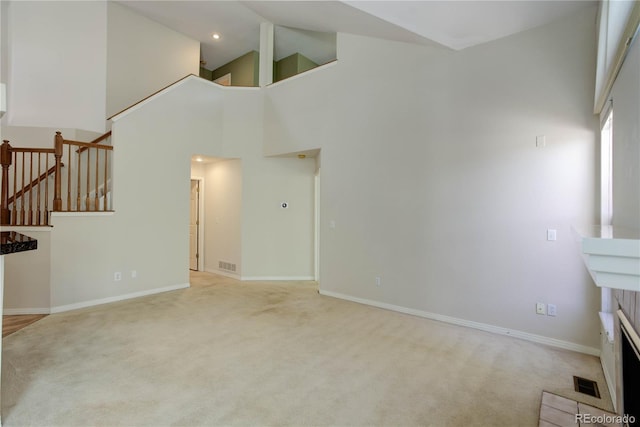 unfurnished living room with light carpet and high vaulted ceiling