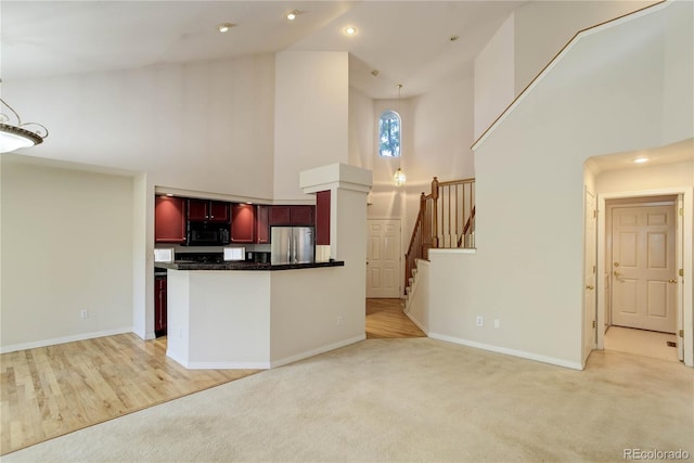 kitchen with stainless steel fridge, pendant lighting, light hardwood / wood-style flooring, and high vaulted ceiling