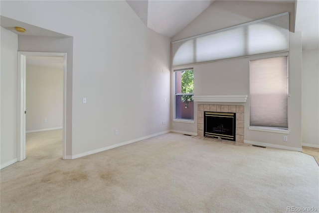 unfurnished living room featuring light carpet, a tiled fireplace, and high vaulted ceiling