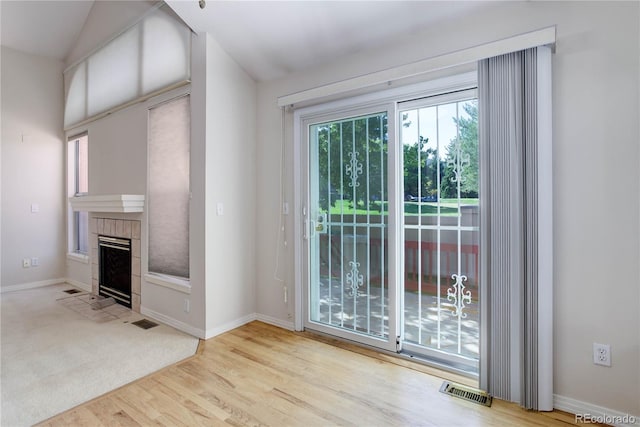 entryway with vaulted ceiling, light hardwood / wood-style floors, and a tile fireplace