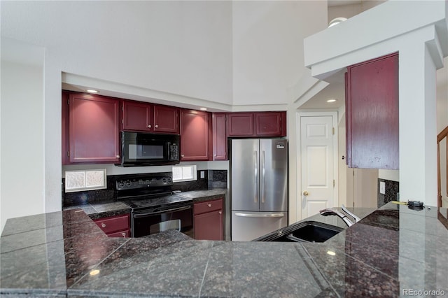 kitchen featuring a towering ceiling, sink, kitchen peninsula, and black appliances