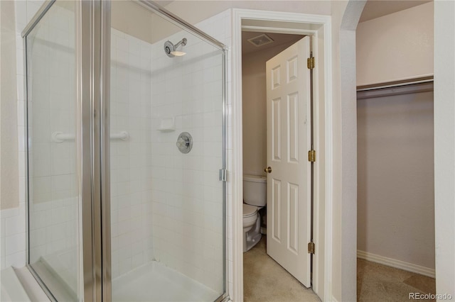 bathroom featuring toilet and a shower with shower door