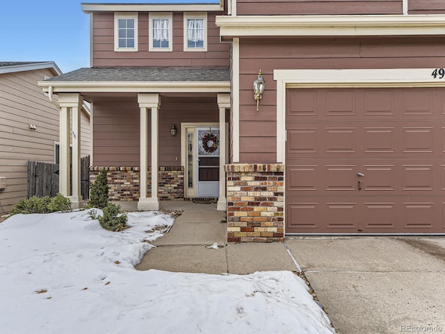 snow covered property entrance with a garage