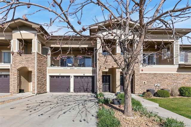 2405 Calais Dr Unit 18A, Longmont, CO 80504 - townhome / multi-family property featuring stone siding, a balcony, an attached garage, concrete driveway, and central air condition unit