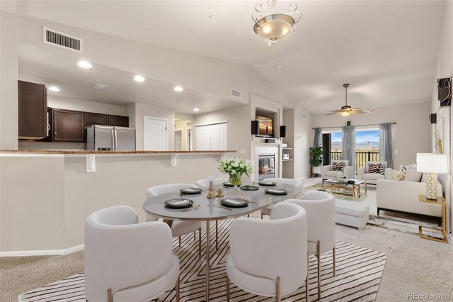 2405 Calais Dr Unit 18A, Longmont, CO 80504 - dining space with light carpet, lofted ceiling, a ceiling fan, and a fireplace
