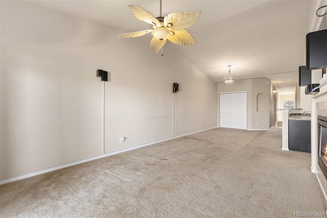2405 Calais Dr Unit 18A, Longmont, CO 80504 - unfurnished living room featuring light colored carpet, vaulted ceiling, baseboards, a ceiling fan, and a warm lit fireplace