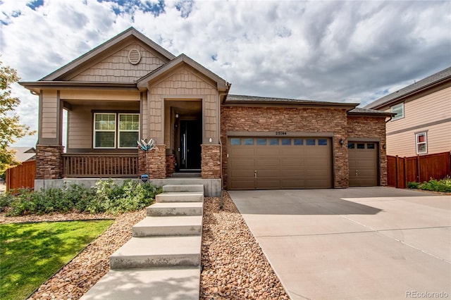 craftsman house with a garage, driveway, fence, and a porch