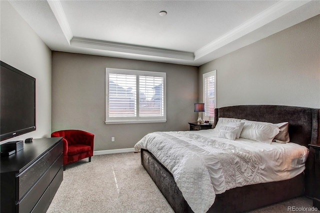 carpeted bedroom with ornamental molding, a tray ceiling, and baseboards