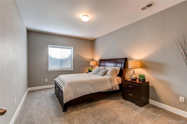 carpeted bedroom with visible vents, a textured wall, and baseboards