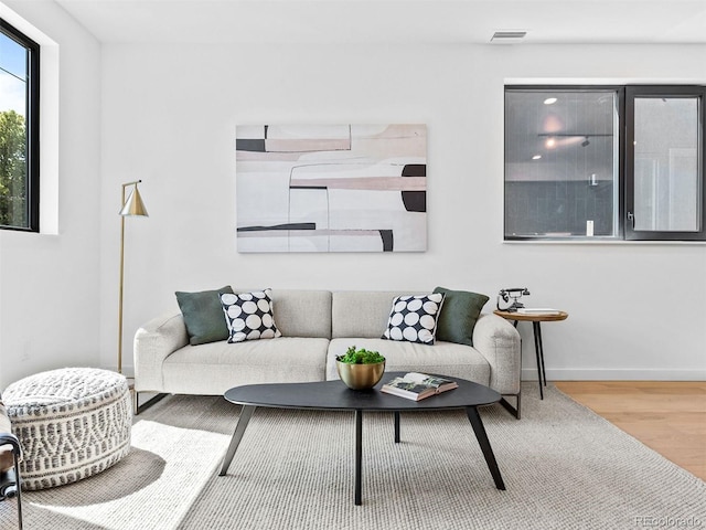 living room featuring wood finished floors, visible vents, and baseboards