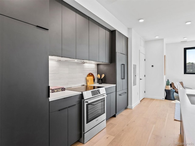1601 Park Ave Unit 212, Denver, CO 80218 - kitchen with decorative backsplash, stainless steel electric stove, gray cabinets, light countertops, and light wood-type flooring