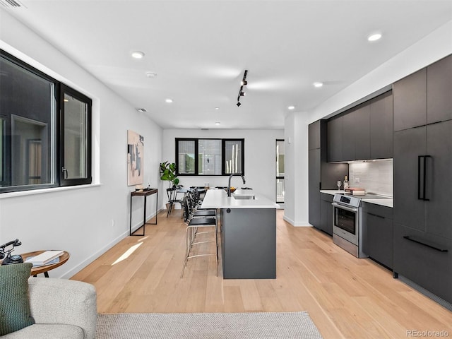 1601 Park Ave Unit 212, Denver, CO 80218 - kitchen with light wood-type flooring, electric range, modern cabinets, and a kitchen breakfast bar