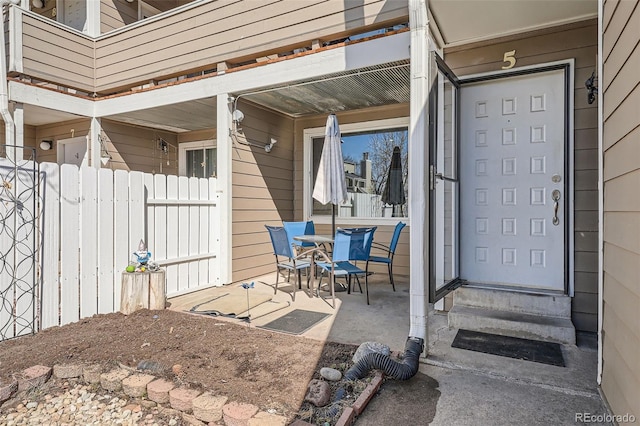 doorway to property with a porch and fence