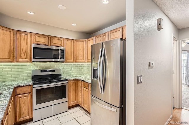 kitchen featuring light tile patterned floors, light stone counters, recessed lighting, stainless steel appliances, and tasteful backsplash