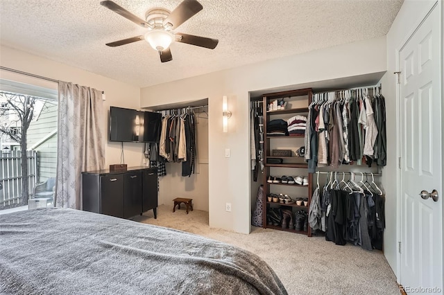 carpeted bedroom featuring a textured ceiling, two closets, and a ceiling fan