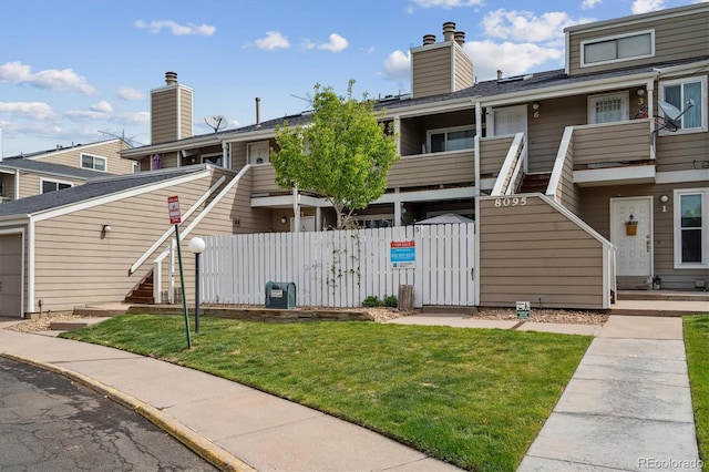 view of front facade featuring fence, stairs, a front yard, a gate, and a chimney