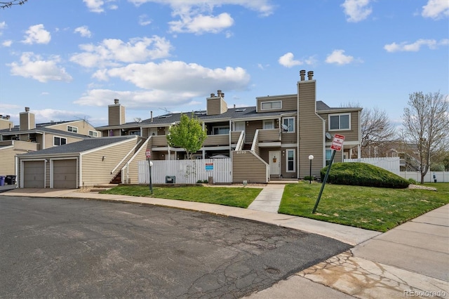 multi unit property with stairway, fence, a residential view, and a front yard