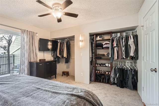 bedroom with a textured ceiling, carpet, ceiling fan, and two closets