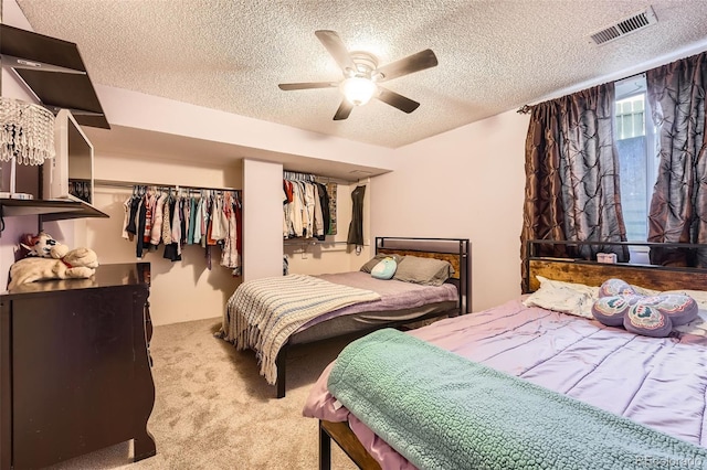 carpeted bedroom featuring ceiling fan, a closet, a textured ceiling, and visible vents