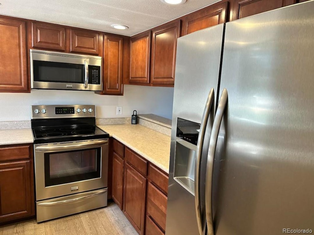 kitchen with stainless steel appliances, recessed lighting, light countertops, and light wood-style floors