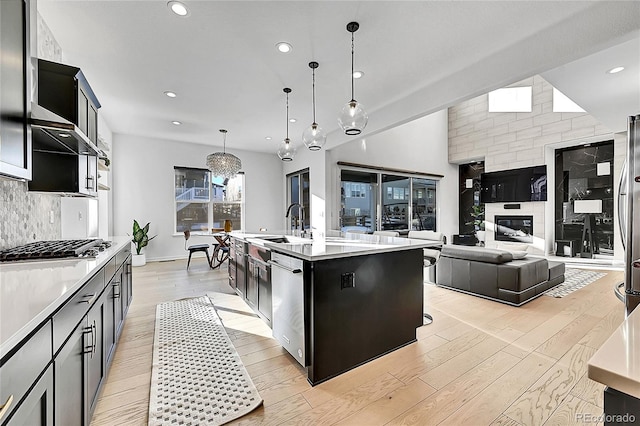 kitchen with light wood-style flooring, appliances with stainless steel finishes, tasteful backsplash, and light countertops