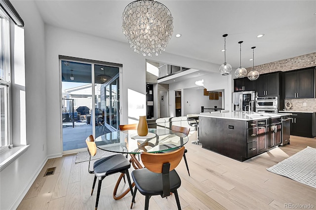 dining area with baseboards, recessed lighting, an inviting chandelier, and light wood-style floors