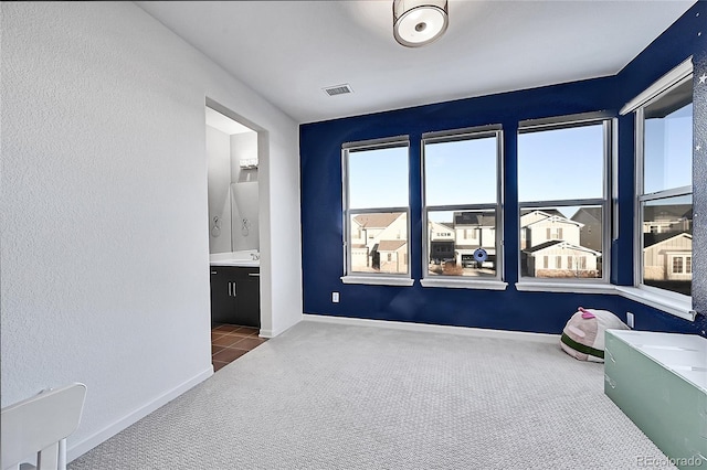 interior space with carpet, visible vents, ensuite bath, and baseboards