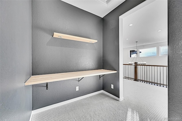 interior space with carpet floors, a notable chandelier, a textured wall, and baseboards