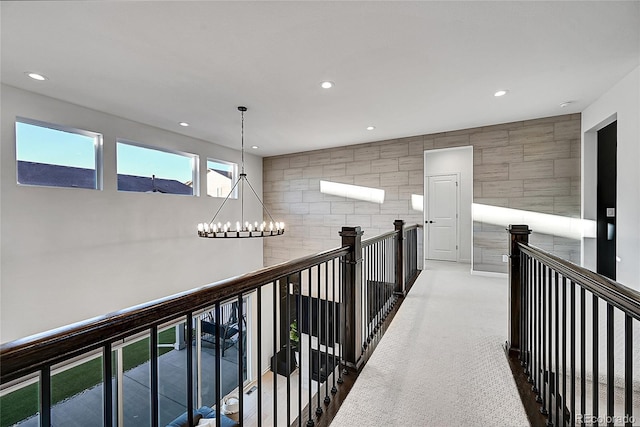 hall featuring recessed lighting, an inviting chandelier, carpet, and an upstairs landing