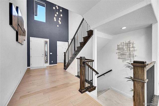 foyer entrance with a high ceiling, baseboards, wood finished floors, and recessed lighting