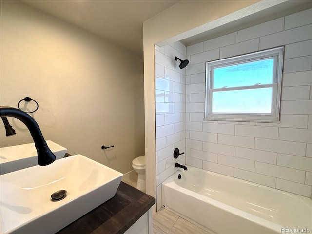 full bathroom featuring tiled shower / bath, sink, and toilet