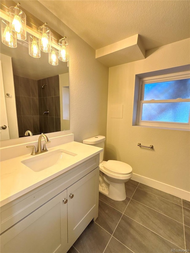 bathroom with toilet, a textured ceiling, a tile shower, vanity, and tile patterned flooring