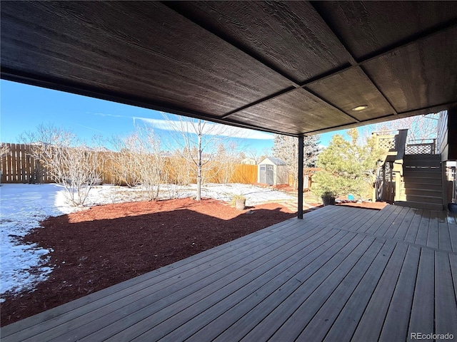 snow covered deck featuring a storage shed