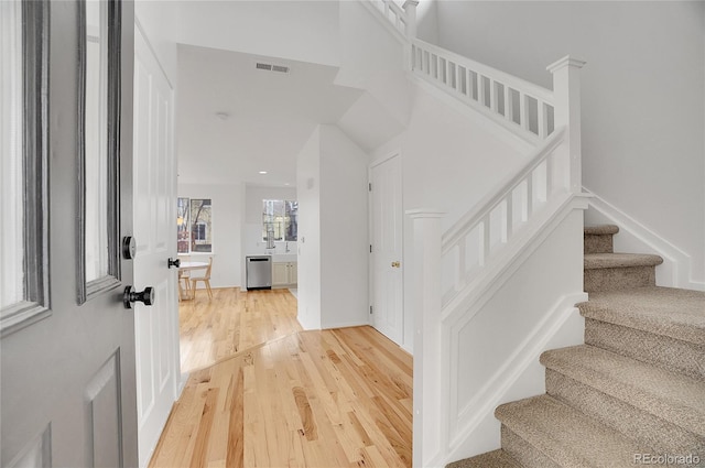 entryway with baseboards, visible vents, stairway, and light wood finished floors