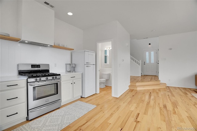 kitchen with visible vents, light wood-style floors, white cabinets, open shelves, and gas range