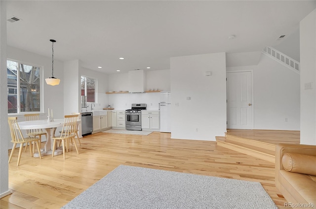 kitchen with open shelves, visible vents, appliances with stainless steel finishes, light wood-style floors, and open floor plan