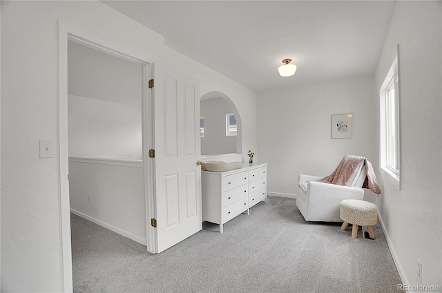 living area with baseboards and light colored carpet