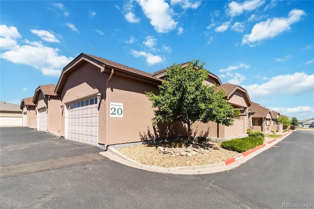 15501 E 112th Ave Unit 20C, Commerce City, CO 80022 - view of property exterior with a residential view, stucco siding, driveway, and an attached garage