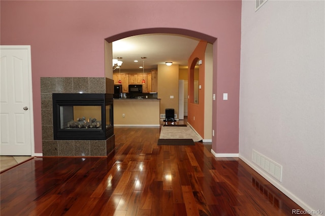 15501 E 112th Ave Unit 20C, Commerce City, CO 80022 - unfurnished living room with arched walkways, dark wood-style flooring, a fireplace, and baseboards