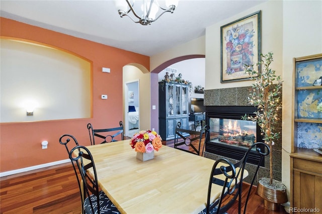 15501 E 112th Ave Unit 20C, Commerce City, CO 80022 - dining room featuring arched walkways, wood finished floors, a fireplace, a chandelier, and baseboards