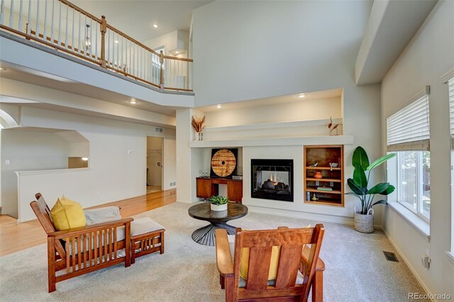 living room featuring light carpet, built in features, and a towering ceiling