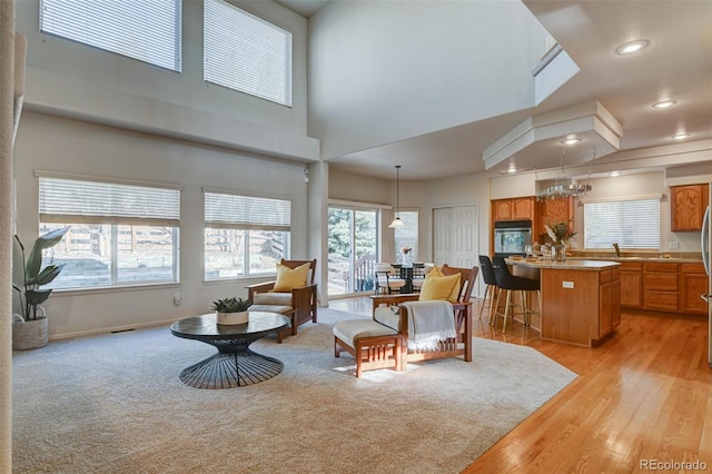 living room featuring light hardwood / wood-style floors, a towering ceiling, and a chandelier