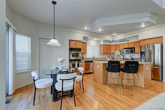 kitchen featuring a kitchen island, light hardwood / wood-style floors, hanging light fixtures, and appliances with stainless steel finishes